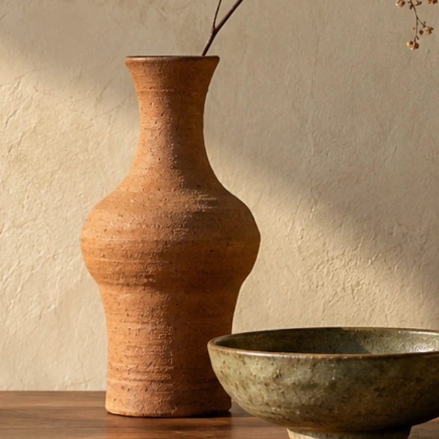 A tall Dune Vase with a warm, textured terracotta finish